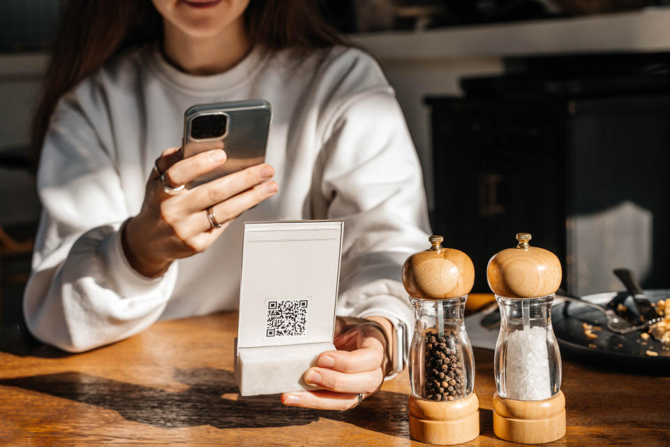 a woman using a QR code from a restaurant menu