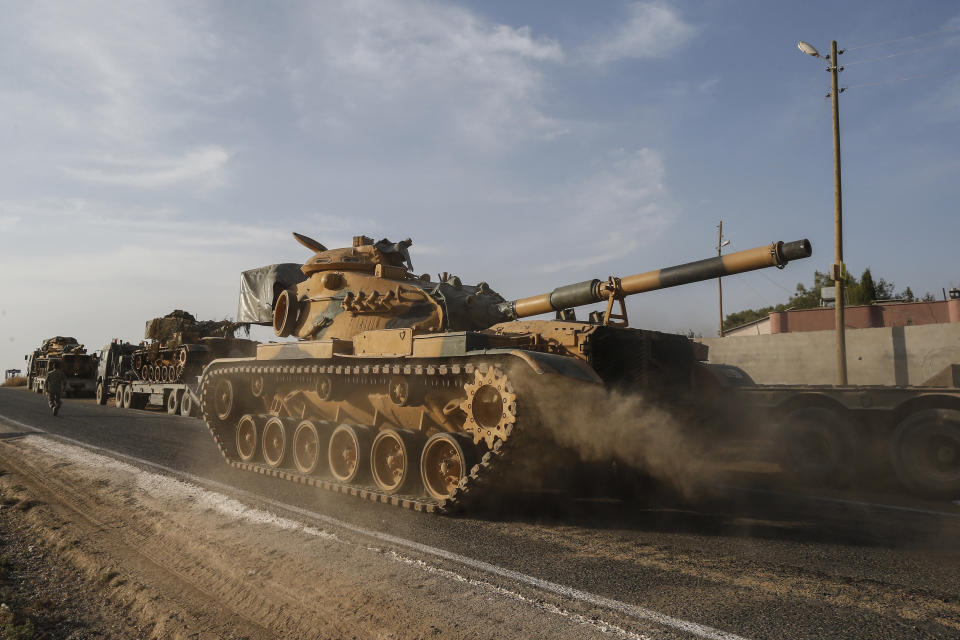 A Turkish forces tank is driven to its new position after was transported by trucks, on a road towards the border with Syria in Sanliurfa province, Turkey, on Monday, Oct. 14, 2019. Syrian troops entered several northern towns and villages Monday, getting close to the Turkish border as Turkey's army and opposition forces backed by Ankara marched south in the same direction, raising concerns of a clash between the two sides as Turkey's invasion of northern Syria entered its sixth day. (AP Photo/Emrah Gurel)