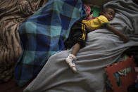 A boy sleeps between his family members as they camp on a footbridge outside the mayor's office in Rio de Janeiro, Brazil, Monday, April 14, 2014. Some of the thousands of people evicted from the abandoned buildings of a telecommunications company on April 11 are camping at the mayor's office, asking for a place to live. (AP Photo/Felipe Dana)