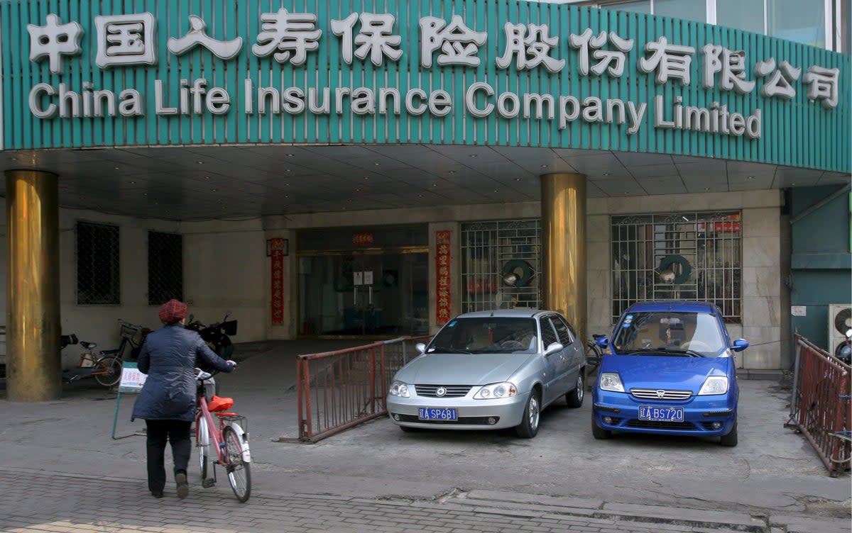 File: A woman walks past a branch of China Life Insurance in Shenyan (EPA)