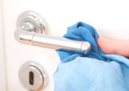 close up of hand cleaning a chrome door handle with blue cloth