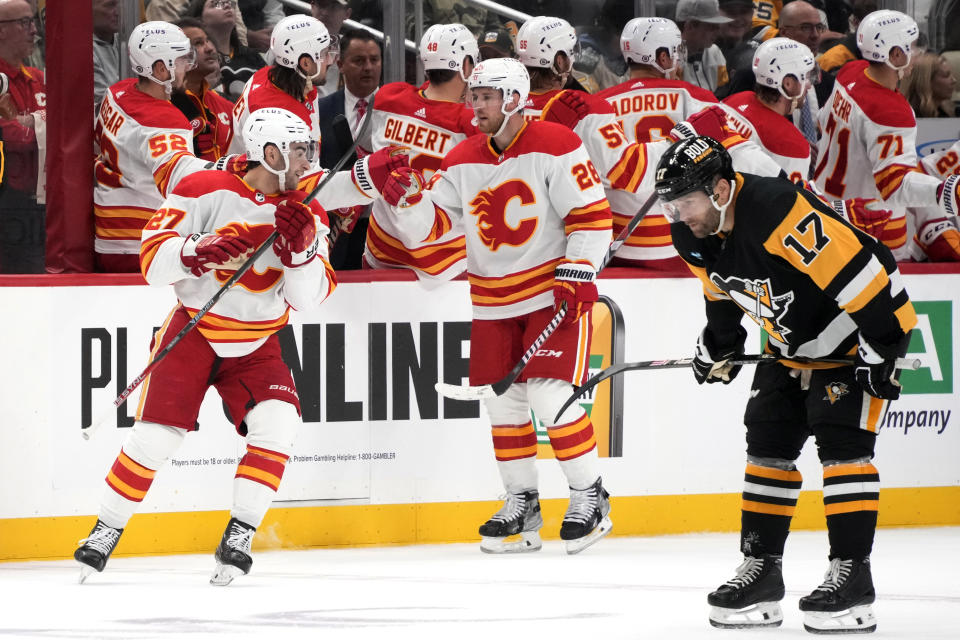 Calgary Flames' Matt Coronato (27) turns after celebrating his goal, while Pittsburgh Penguins' Bryan Rust (17) skates back to the bench during the second period of an NHL hockey game in Pittsburgh, Saturday, Oct. 14, 2023. (AP Photo/Gene J. Puskar)