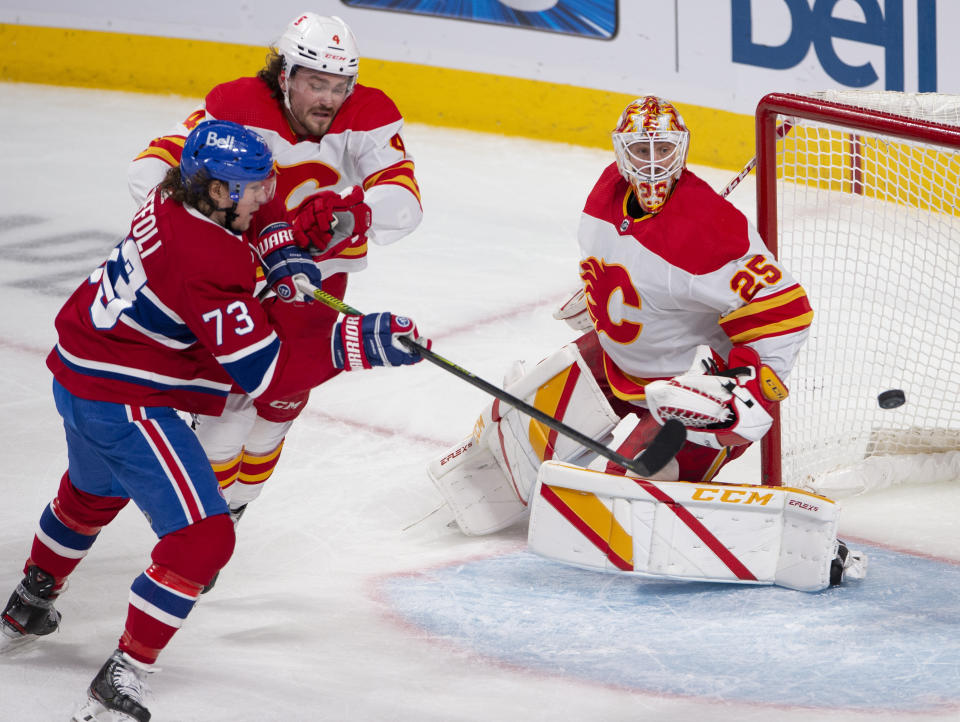 Montreal Canadiens' Tyler Toffoli (73) tries to knock in a loose puck as Calgary Flames goaltender Jacob Markstrom (25) and Flames' Rasmus Andersson (4) look on during the second period of an NHL hockey game Wednesday, April 14, 2021 in Montreal. (Ryan Remiorz/Canadian Press via AP)