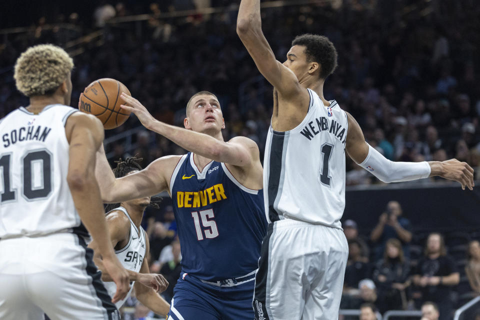 Denver Nuggets center Nikola Jokic (15) looks for the basket between San Antonio Spurs forward Jeremy Sochan (10) and center Victor Wembanyama (1) during the first half of an NBA basketball game, Friday, March 15, 2024, in Austin, Texas. (AP Photo/Stephen Spillman)