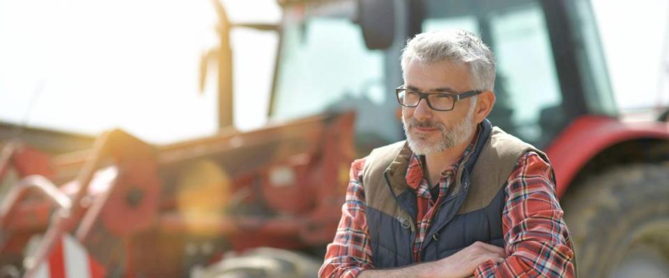 Farmer standing by tractor outside the barn