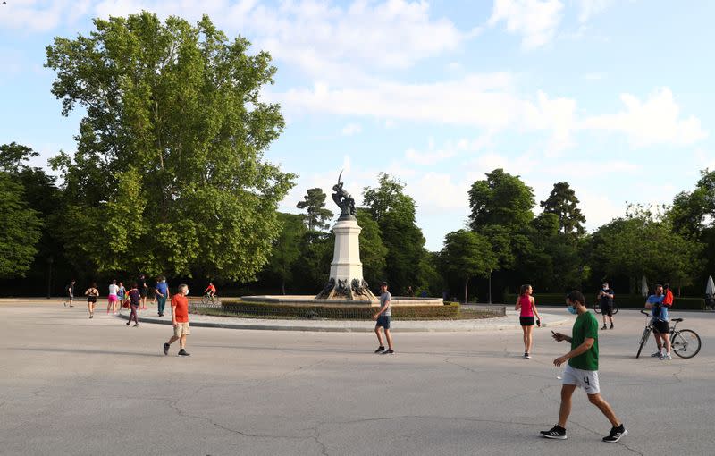 People walk past the Fountain of the Fallen Angel as they enjoy the sunny weather at Retiro Park amid the coronavirus disease (COVID-19) outbreak in Madrid