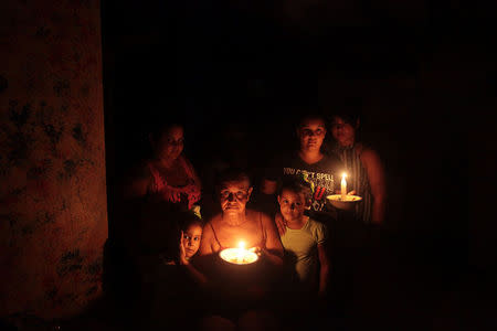 A family poses with candles in the darkness of their home after Hurricane Maria hit the island and damaged the power grid in September, in Vega Alta, Puerto Rico October 30, 2017. REUTERS/Alvin Baez