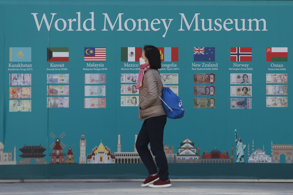 A woman walks by a board displaying various banknotes issued in the world in Seoul, South Korea, Wednesday, Feb. 5, 2020. Asian shares rose Wednesday on optimism that China's latest actions may help curtail some of the expected economic damage from the virus outbreak. (AP Photo/Ahn Young-joon)