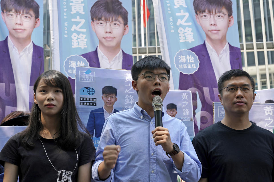 El activista prodemocracia de Hong Kong, Joshua Wong (centro), escoltado por Agnes Chow (izquierda) y el activista prodemocracia Au Nok-hin, habla con periodistas en Hong Kong, el 28 de septiembre de 2019. (AP Foto/Kin Cheung)