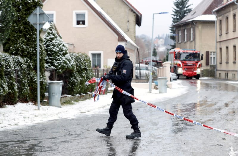 A police officer cordons off the area next to a home for people with disabilities which was affected by a fire, in Vejprty