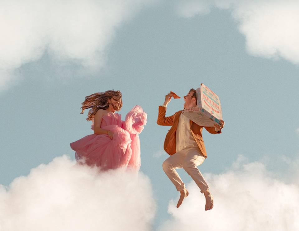 The couple appear to be suspended in a cloudy sky