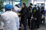 A medical official takes the body temperature of a man at the departure hall of the airport in Changsha