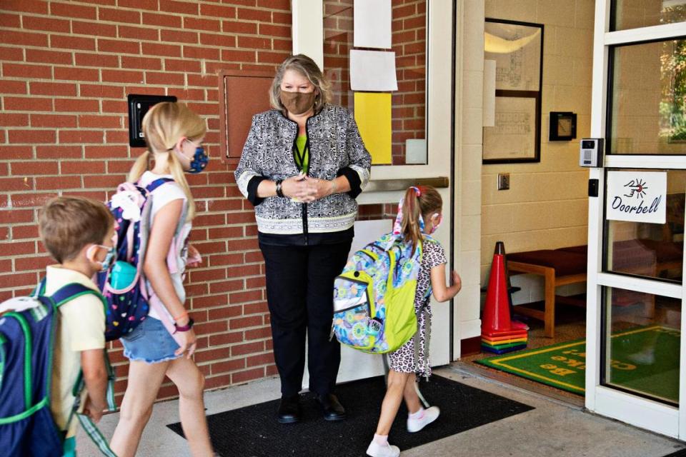 Principal Fay Jones, center, greets students as they enter Carpenter Elementary School in Cary on Thursday morning, Aug. 19, 2021. A change in how North Carolina calculates pay could cost principals thousands of dollars. .