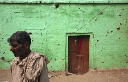 A villager stands next to the wall of a house that locals say was damaged by firing from the Pakistan side of the border at Arnia village, near Jammu October 6, 2014. REUTERS/Mukesh Gupta