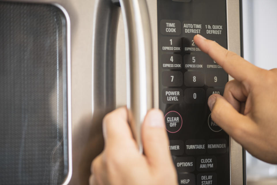 A person uses a microwave.