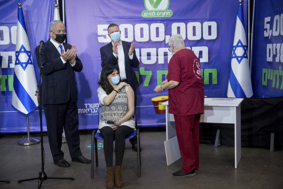 Israeli Prime Minister Benjamin Netanyahu, left, and Health Minister Yuli Edelstein, center, meet the Israeli citizen, center, who is the 5 millionth person to be vaccinated in Israel, in Tel Aviv, Israel, Monday, March 8, 2021. (Miriam Alster/Pool via AP)