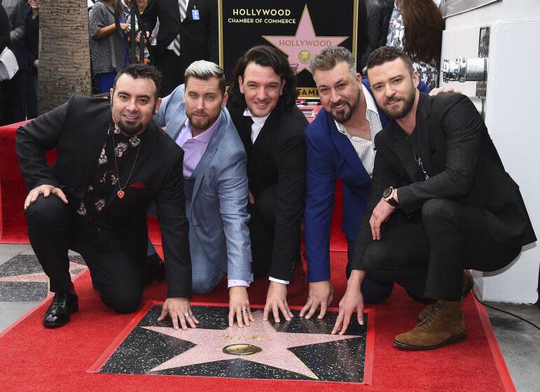 NSYNC's Chris Kirkpatrick, Lance Bass, JC Chasez, Joey Fatone and Justin Timberlake smile and crouch by a Walk of Fame star