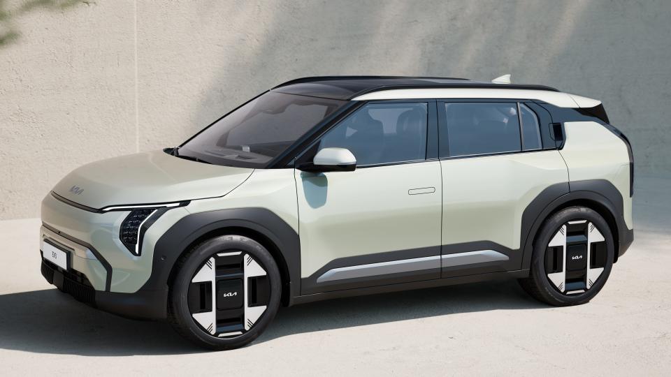 A Kia EV3 compact electric SUV is parked in front of a building.