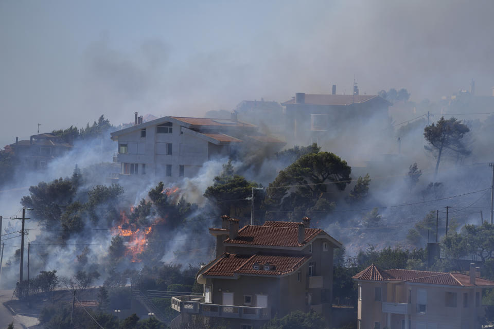 El fuego arde junto a viviendas en la zona de Drafi, al este de Atenas, el miércoles 20 de julio de 2022. Cientos de personas fueron evacuadas de sus hogares el martes por la noche por un incendio que amenazaba a suburbios al nordeste de Atenas. (AP Foto/Thanassis Stavrakis)