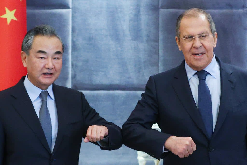 China's Foreign Minister Wang Yi (L) and his Russian counterpart Sergei Lavrov bump elbows as they meet for talks (Russian Foreign Ministry/TASS)