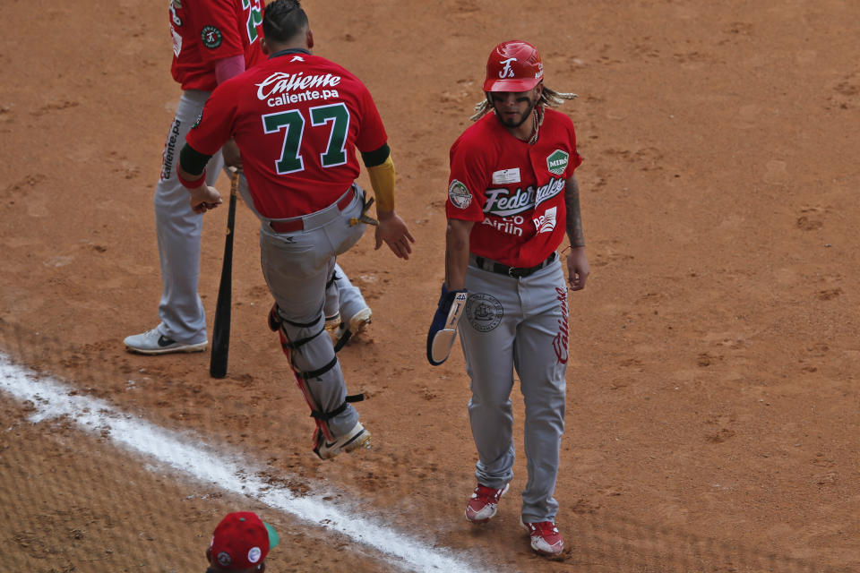 Los panameños Jonathan Aráuz (derecha) y Rodrigo Vigil celebran la anotación de una carrera en el juego contra Colombia por la Serie del Caribe en Mazatlán, México, el lunes 1 de febrero de 2021. (AP Foto/Moisés Castillo)