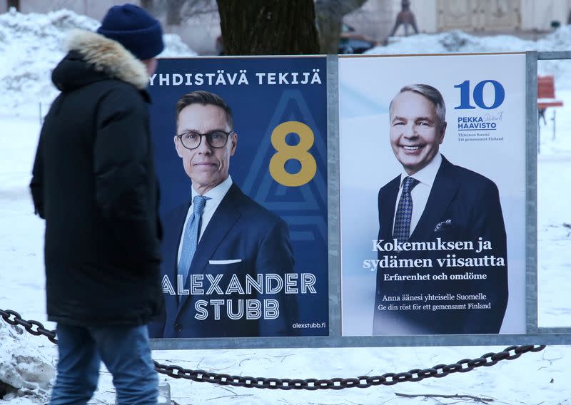 A pedestrian stands next to posters of the candidates in the second round of the Finnish presidential elections in Helsinki