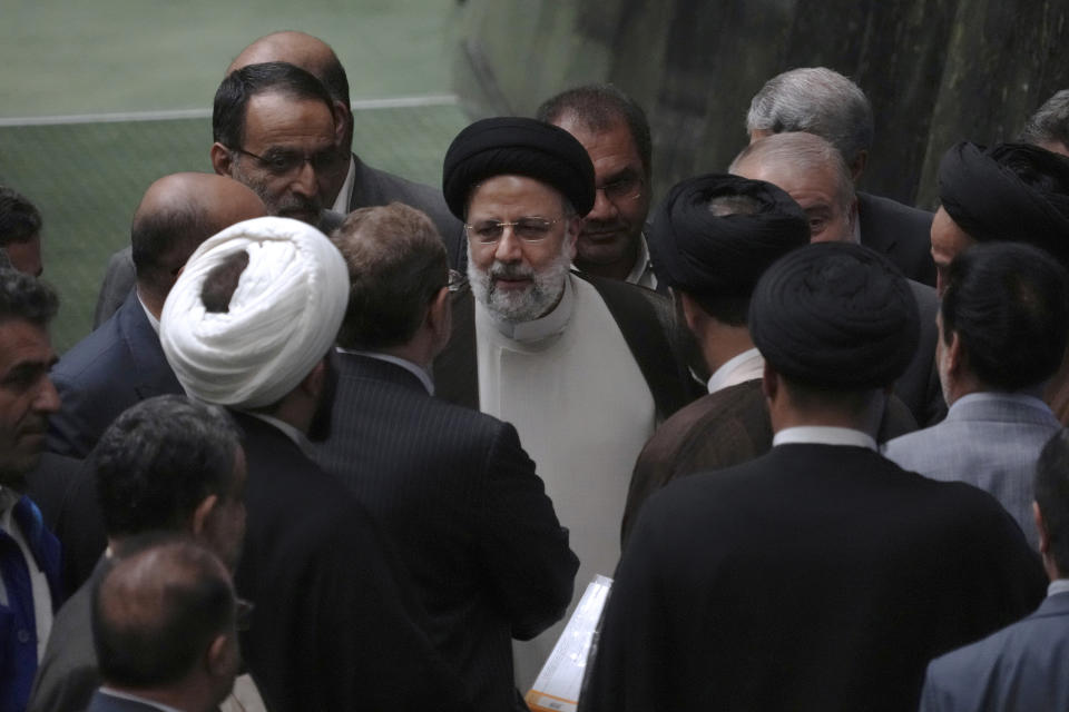 Iranian President Ebrahim Raisi is surrounded by a group of lawmakers after defending his proposed labor minister in a vote of confidence session at the parliament in Tehran, Iran, Tuesday, Oct. 4, 2022. (AP Photo/Vahid Salemi)