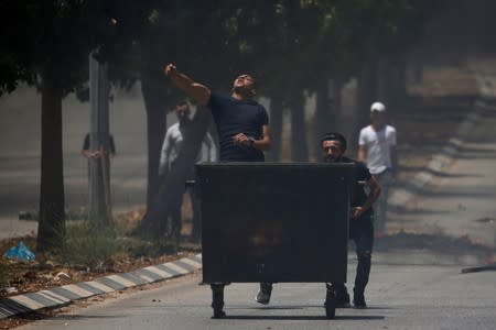 Palestinian demonstrator hurls stones at Israeli forces during a protest against Bahrain's workshop for U.S. peace plan, near Hebron, in the Israeli-occupied West Bank