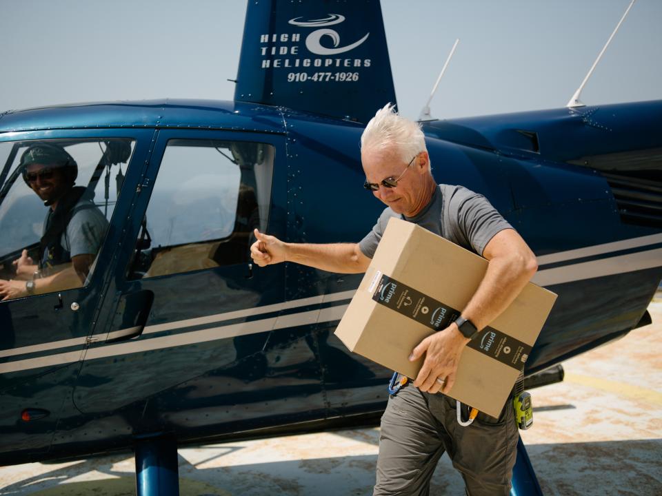 Richard Neal picks up an Amazon package via helicopter at Frying Pan Tower.