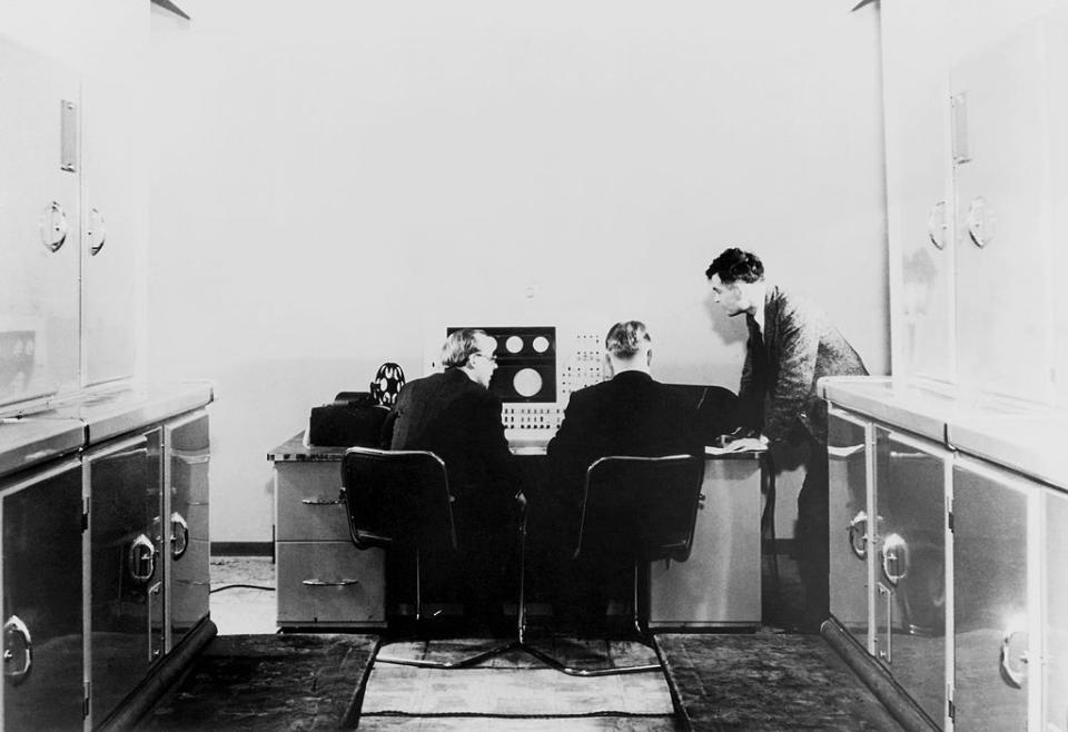 Alan Turing in piedi, mentre lavora con dei colleghi su un elaboratore elettronico.  (Photo by SSPL/Getty Images)