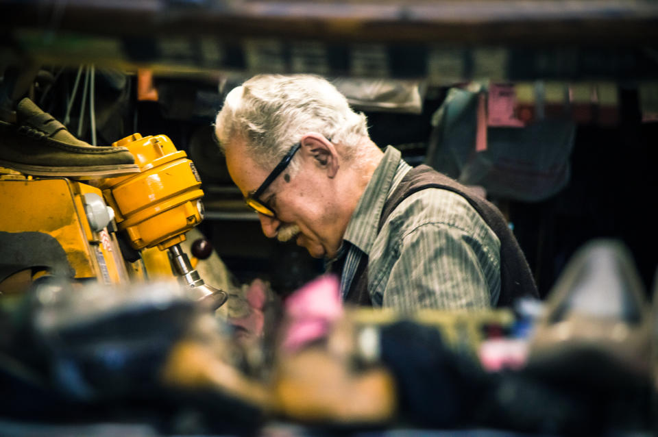 A senior entrepreneur shoemaker in his shoe repair shop.