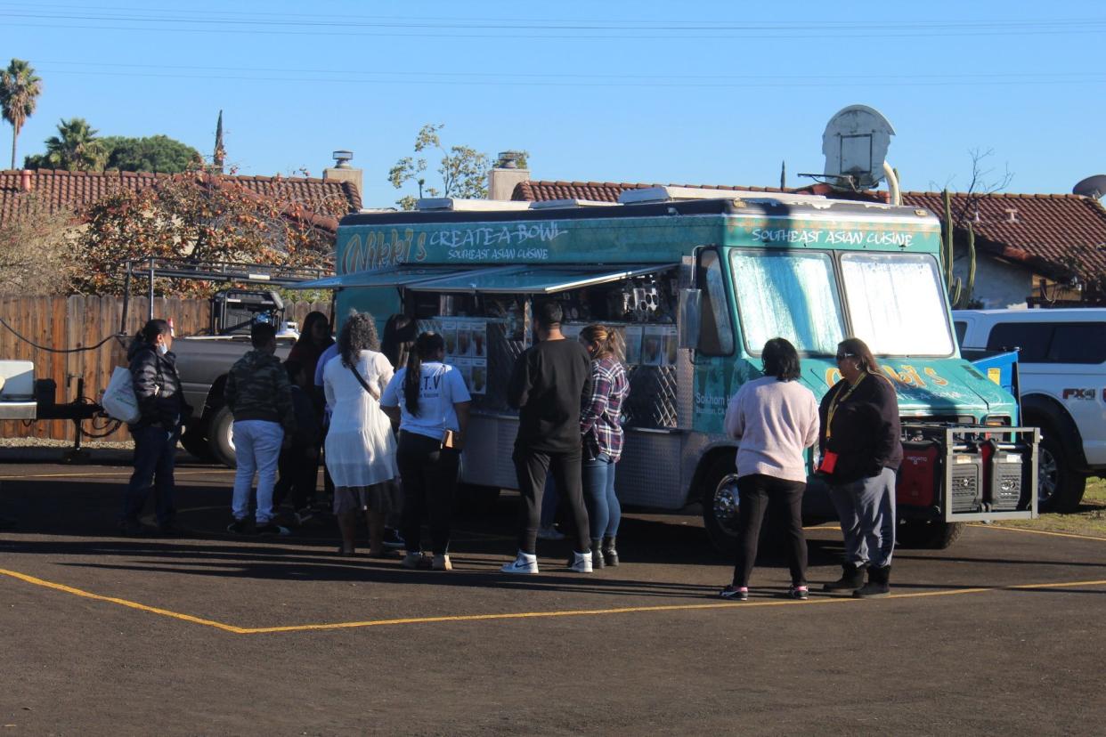 People wait in line for free food from Nikki's Create-A-Bowl Southeast Asian Cuisine. The food truck was one of two stationed at the Asian Health and Healing Clinic held at Trinity Presbyterian Church in south Stockton on Nov. 13, 2022.