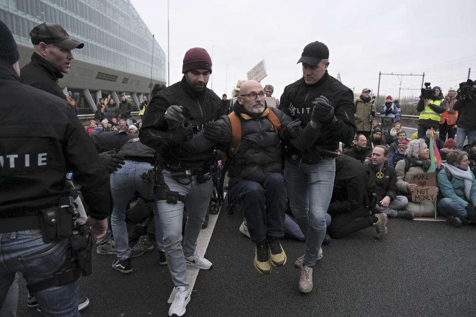 Police detain climate activists blocking the main highway around Amsterdam near the former headquarters of a ING bank to protest its financing of fossil fuels, Saturday, Dec. 30, 2023. Protestors walked onto the road at midday, snarling traffic around the Dutch capital in the latest road blockade organized by the Dutch branch of Extinction Rebellion. (AP Photo/Patrick Post)