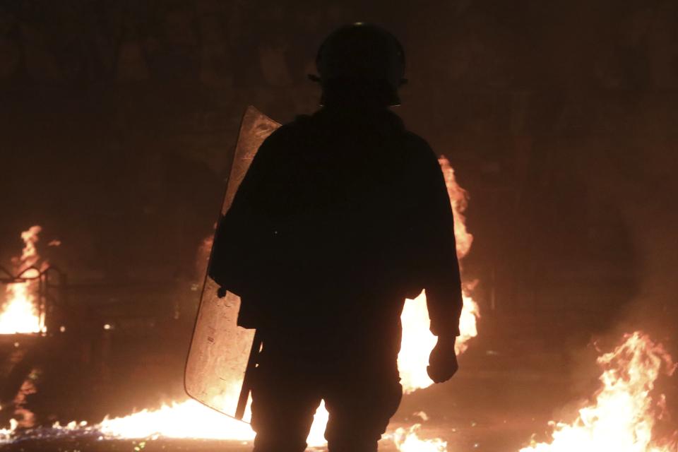 A riot policeman stands among fires from petrol bombs during clashes in the Athens neighborhood of Exarchia, a haven for extreme leftists and anarchists, Saturday, Nov. 17, 2018. Clashes have broken out between police and anarchists in central Athens on the 45th anniversary of a student uprising against Greece's then-ruling military regime. (AP Photo/Yorgos Karahalis)