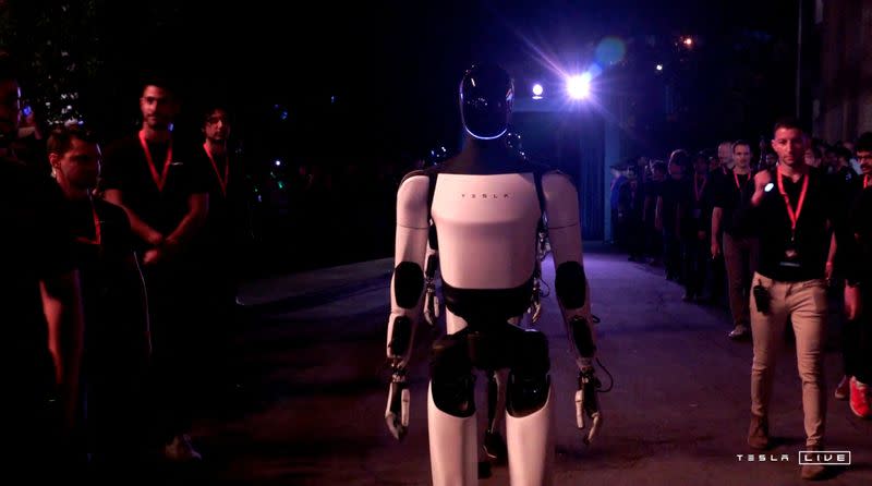 Tesla's Optimus robots walk on the day of an unveiling event in Los Angeles