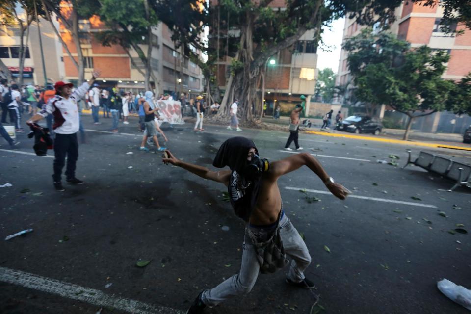 A demonstrator throws stones at the National Bolivarian Police (BNP) after clashes broke out at an opposition protest in Caracas, Venezuela, Saturday, Feb. 15, 2014. Venezuelan security forces backed by water tanks, tear gas and rubber bullets dispersed groups of anti-government demonstrators who tried to block Caracas' main highway Saturday evening. (AP Photo/Fernando Llano)