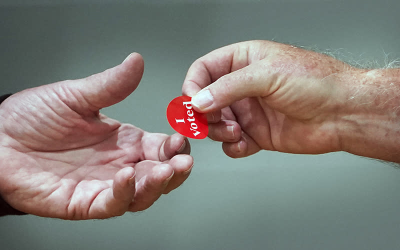 An election worker hands a voting sticker to a voter