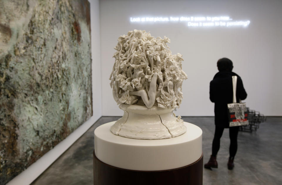 A visitor looks at artwork beside a piece by  British artist Rachel Kneebone, center, inside the White Cube gallery in Hong Kong Thursday, March 1, 2012. Britain's White Cube gallery, known as an early champion of provocative British artists Damien Hirst and Tracey Emin, launched its Hong Kong branch on Thursday, becoming the latest Western gallery to open an Asian outpost in pursuit of China's booming art market.  (AP Photo/Kin Cheung)