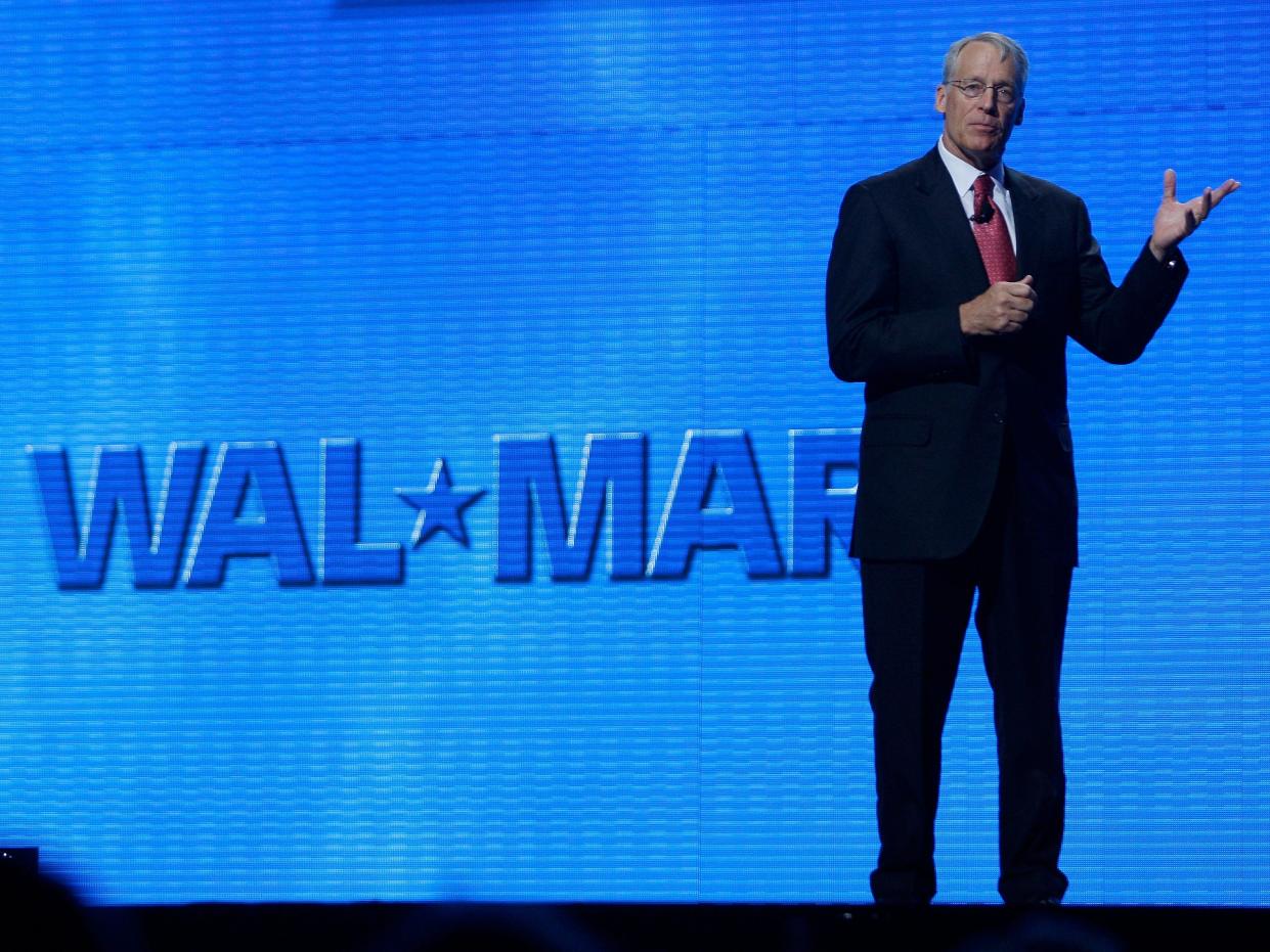 Rob Walton gestures onstage in front of blue Walmart logo