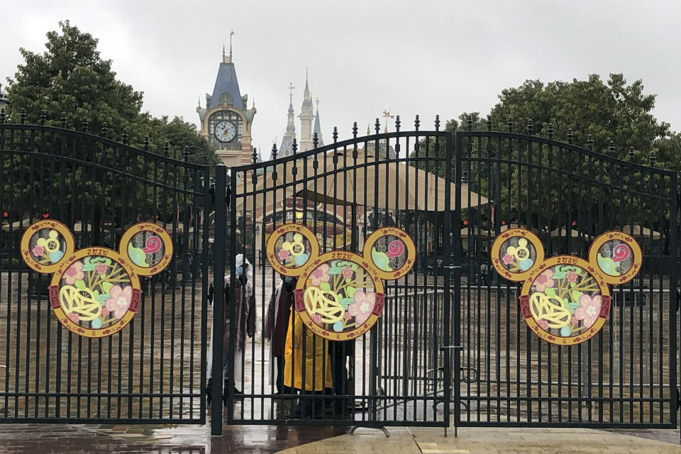 Employees stand at the gates of the Shanghai Disney Resort, which announced that it will be closed indefinitely from Saturday, in Shanghai, Saturday, Jan. 25, 2020. China's most festive holiday began in the shadow of a worrying new virus Saturday as the death toll surpassed 40, an unprecedented lockdown that kept people from traveling was expanded to more than 50 million residents and authorities canceled a host of Lunar New Year events. (AP Photo/Fu Ting)