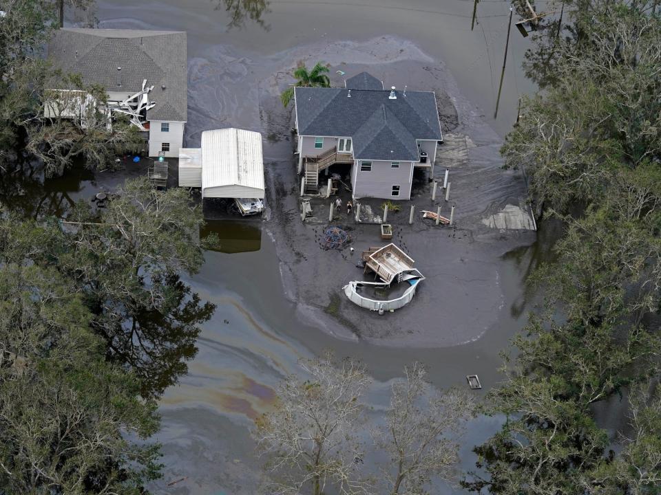 oil slick rainbow sheen in floodwaters drifting past a home on stilts in lafitte louisiana