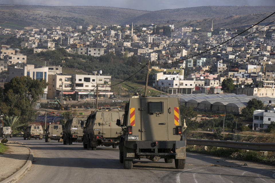 A convoy of Israeli army vehicles is seen during a military raid into Faraa refugee camp, West Bank, Friday, Dec. 8, 2023. The Palestinian Health Ministry says that five Palestinians were killed when Israeli forces raided the camp prompting fighting with local militants. (AP Photo/Majdi Mohammed)