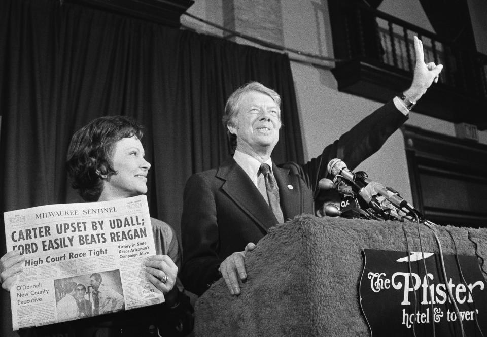 Jimmy Carter hace la señal de la victoria mientras su esposa, Rosalynn Carter, sostiene un periódico después de ganar la primaria presidencial demócrata de Wisconsin el 7 de abril de 1976. (AP Foto/Paul Shane, Archivo)