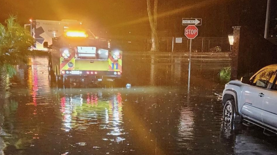 Emergency vehicles and motorists try to navigate a flooded street in Ventura County.