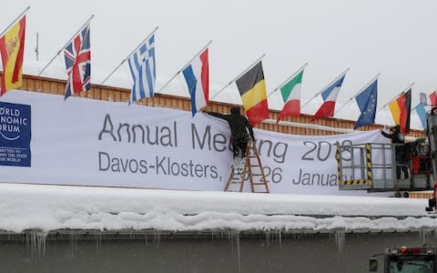 Workers fix a banner on the frontage of the congress centre in the Swiss mountain resort of Davos