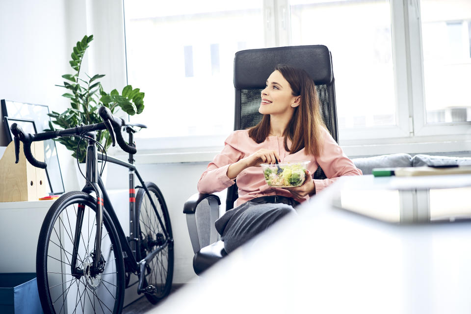 Businesswoman having lunch break in office sitting at desk. Image: Getty Images