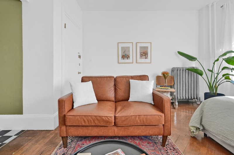 Leather couch on a rug in a studio apartment.