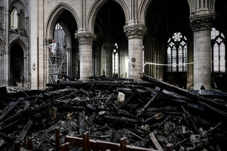 A worker stands on scaffolding near the rubbles and damages during the preliminary work in the Notre-Dame Cathedral one month after it sustained major fire damage in Paris, France May 15, 2019. Philippe Lopez/Pool via REUTERS