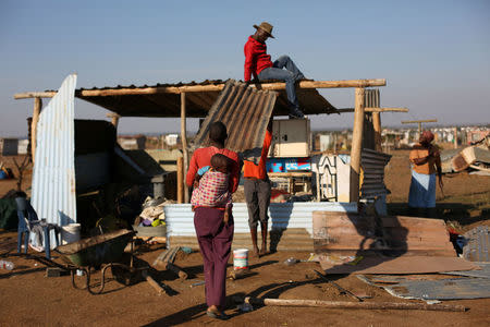 A woman works to rebuild her home, which was damaged during the demolition of shacks, which triggered riots, north of the South African capital Pretoria, May 24, 2016. REUTERS/Siphiwe Sibeko