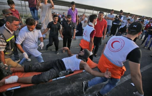 Palestinian paramedics carry an injured protester as people demonstrate at the Erez border crossing with Israel in the northern Gaza Strip on October 3, 2018